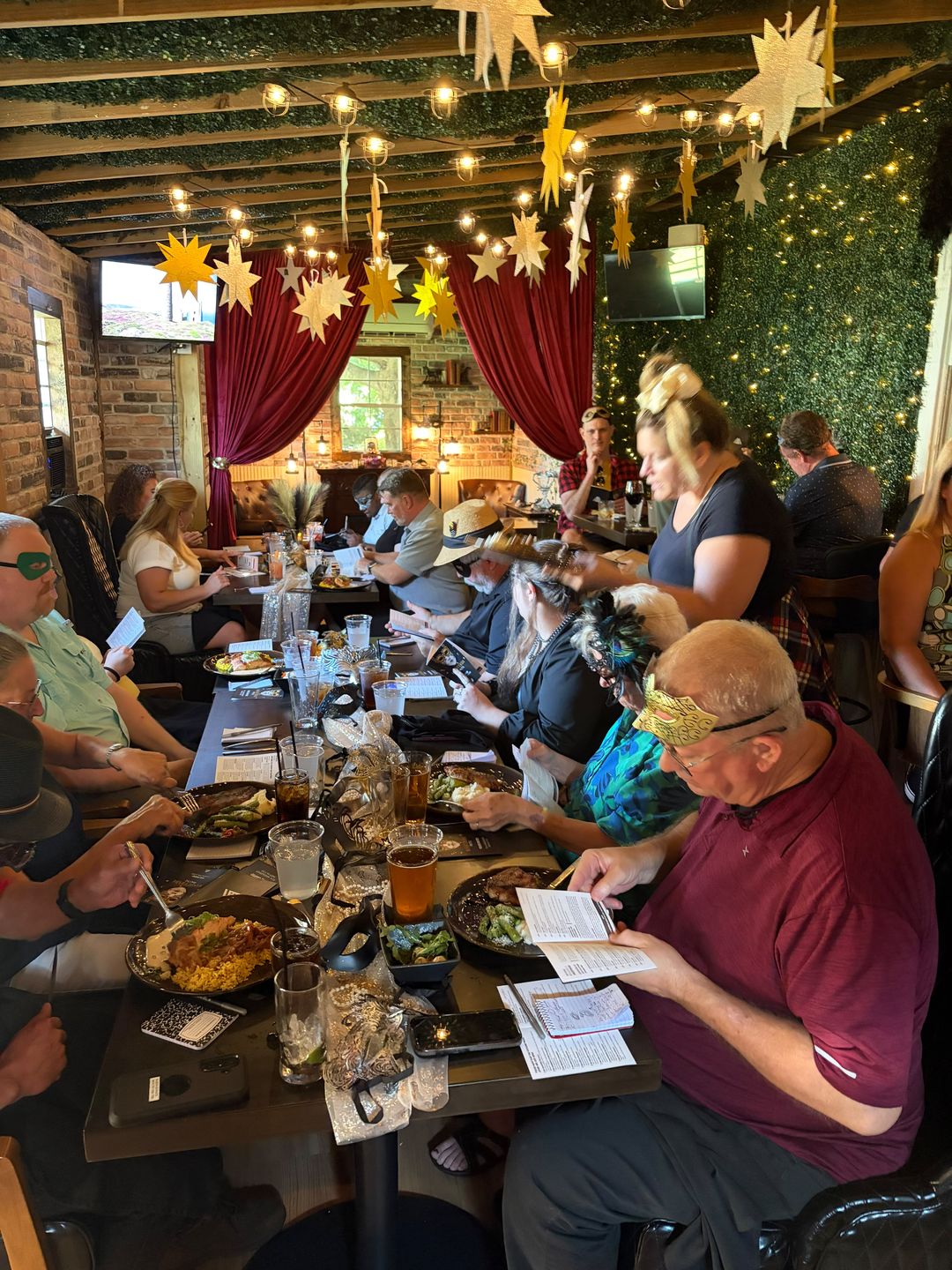 Guests in masquerade masks reading clue sheets over dinner at a Murder Mystery Dinner in Smithfield, VA